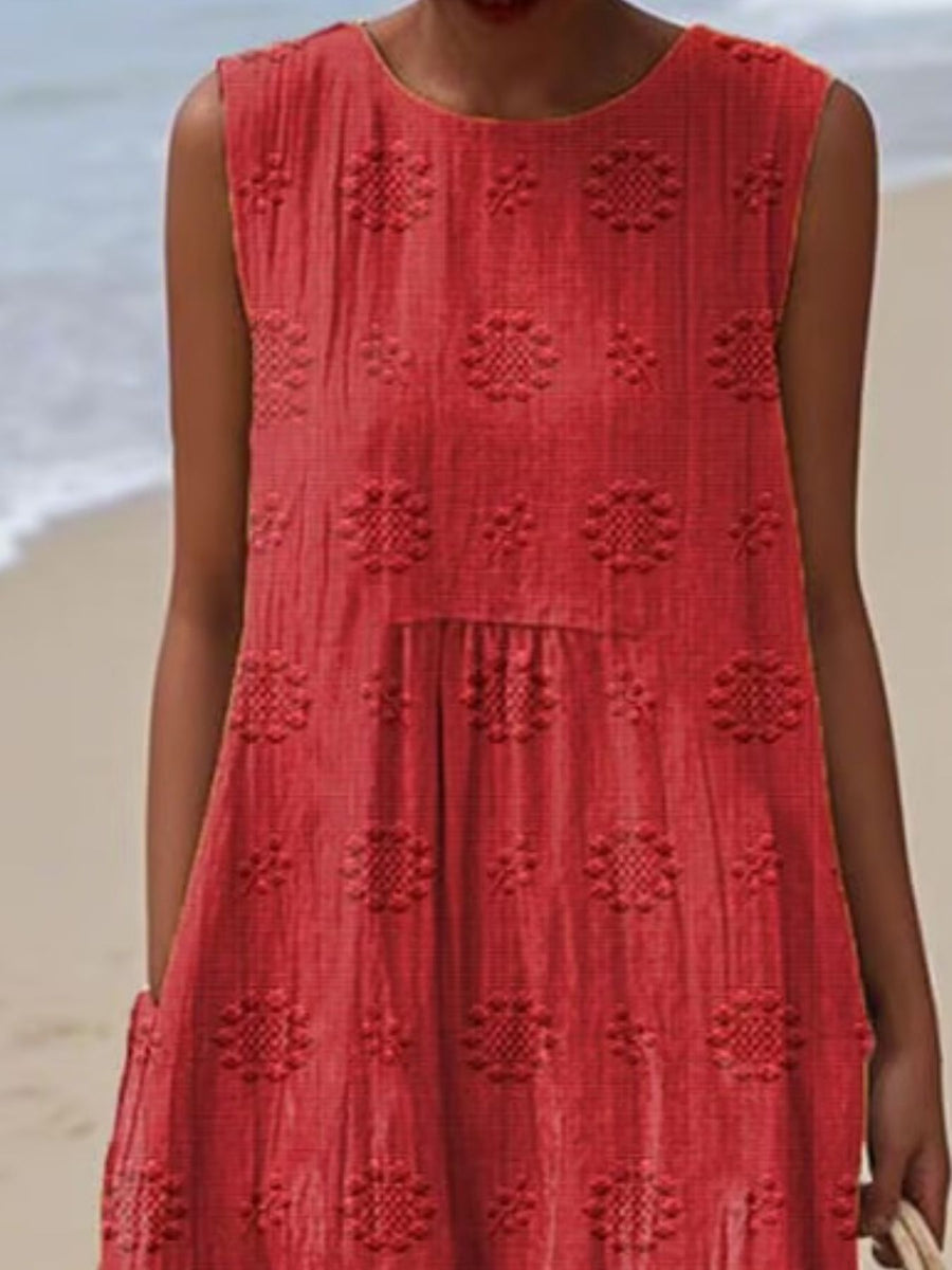 Red dress with a textured pattern worn by a person on a beach.