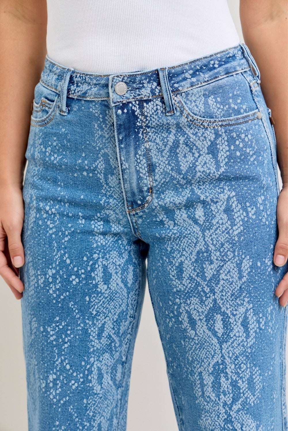 Blue acid-wash jeans worn by a person on a neutral background