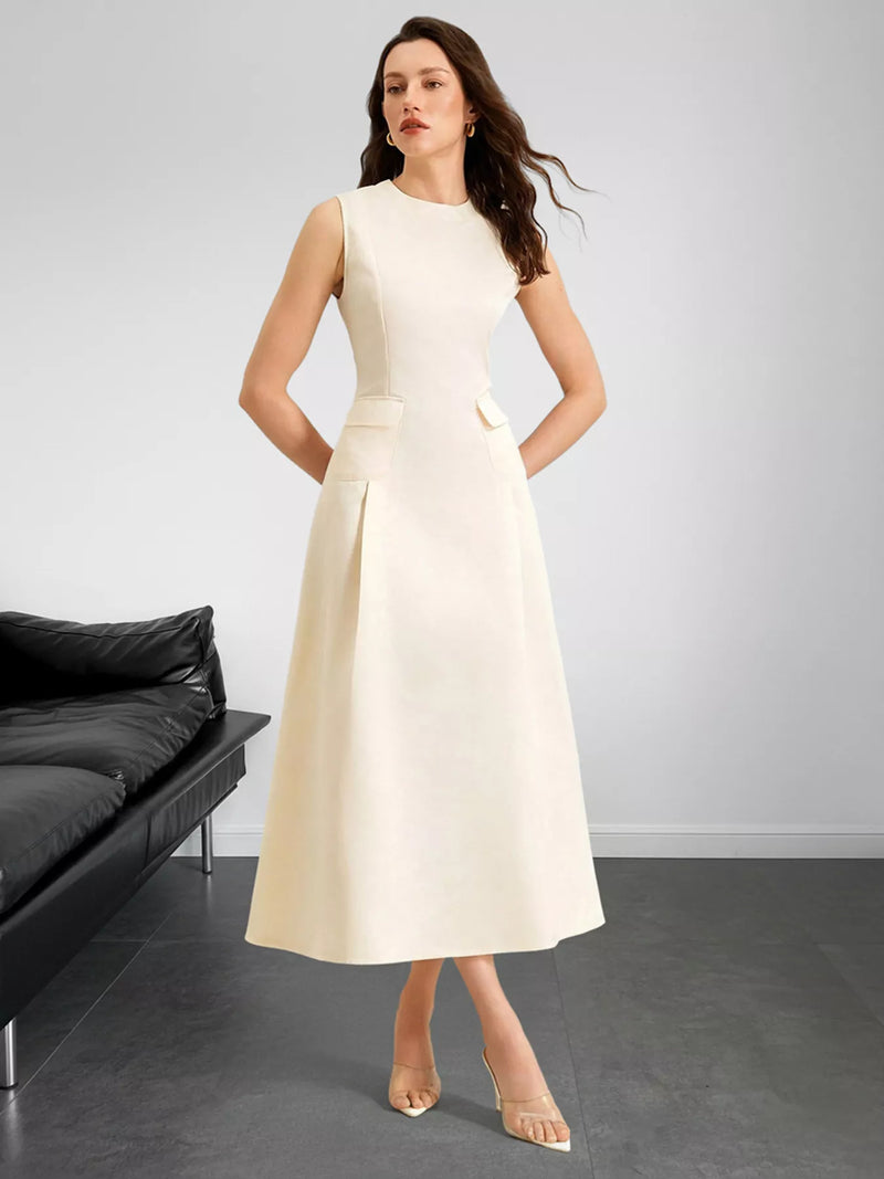 Woman wearing a white dress standing in a minimalistic room with a black sofa.