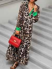 Person wearing a leopard print dress with green accents and holding a red handbag on a staircase.