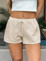 Person wearing beige checkered shorts with a blurred background