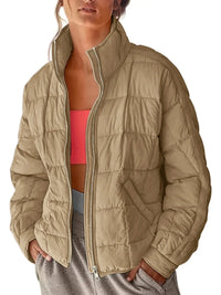 Person wearing a beige puffer jacket over a pink sports bra and gray pants on a white background