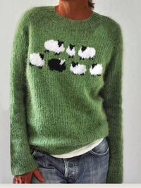 Green sweater with sheep pattern worn by a person against a plain background