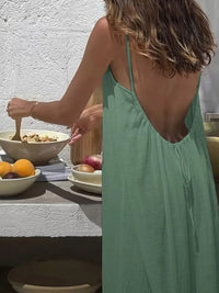 Woman in a green dress standing at a table with food items.