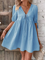Woman wearing a blue dress with a wooden and brick wall background