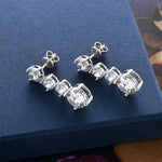 Silver earrings with clear stones on a blue surface