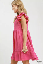 Woman wearing a pink dress with ruffled sleeves on a white background