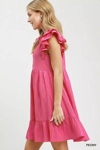 Woman wearing a pink dress with ruffled sleeves on a white background