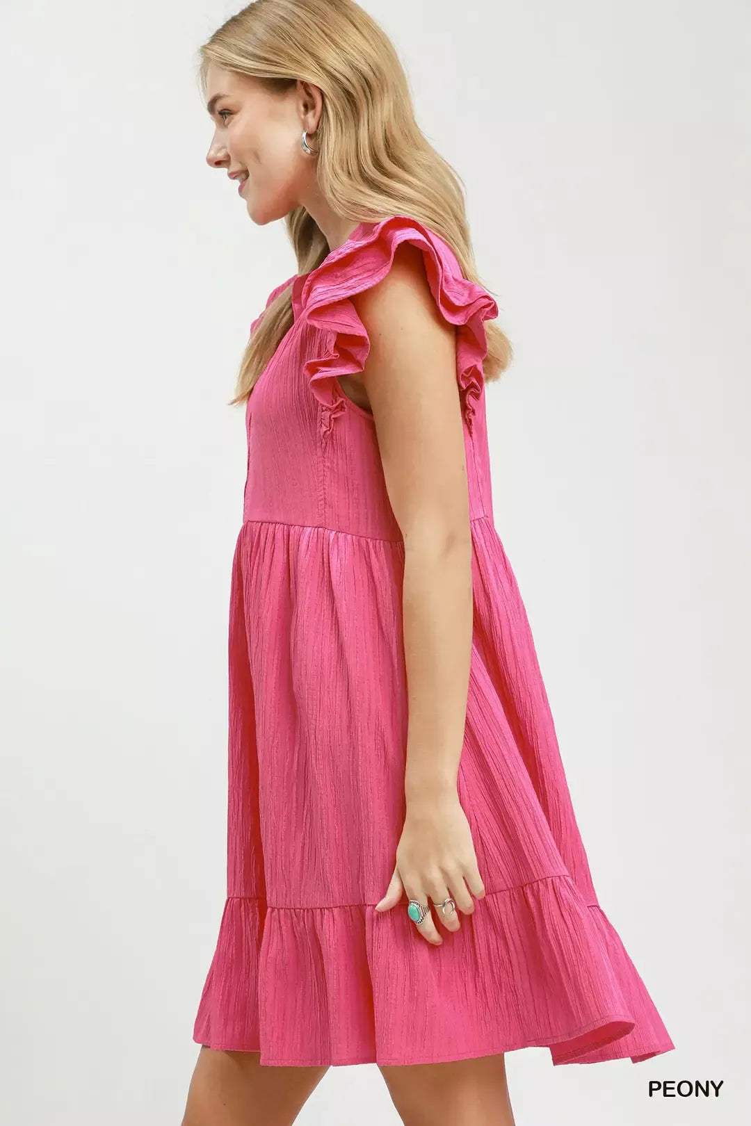 Woman wearing a pink dress with ruffled sleeves on a white background