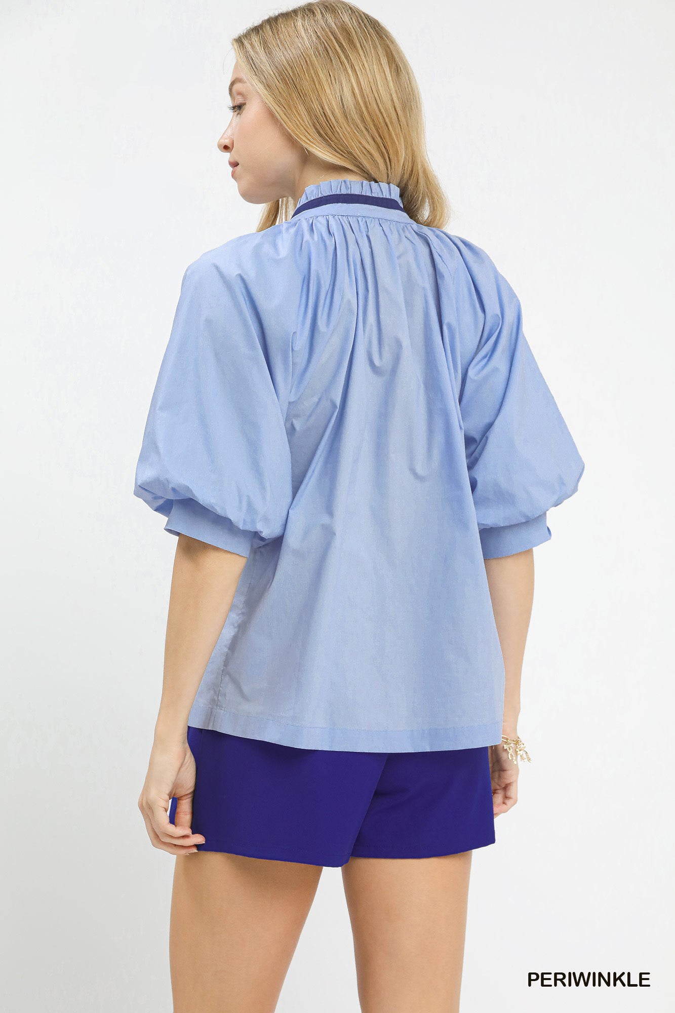 Woman wearing a light blue blouse and purple shorts on a white background