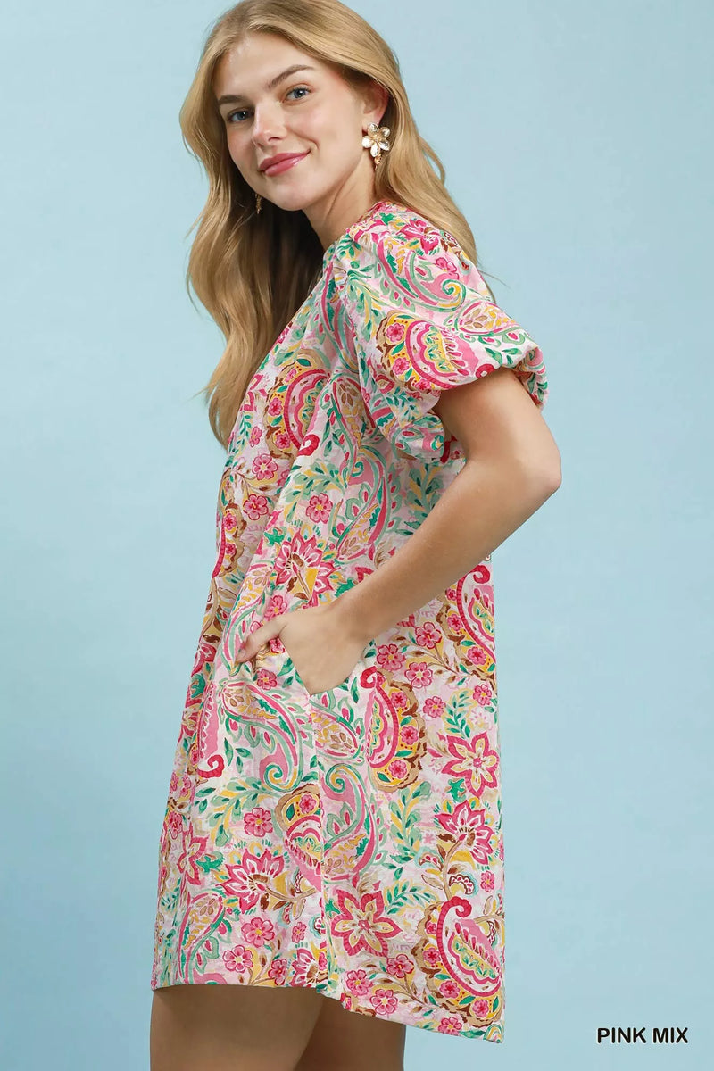 Woman wearing a colorful paisley dress against a light blue background