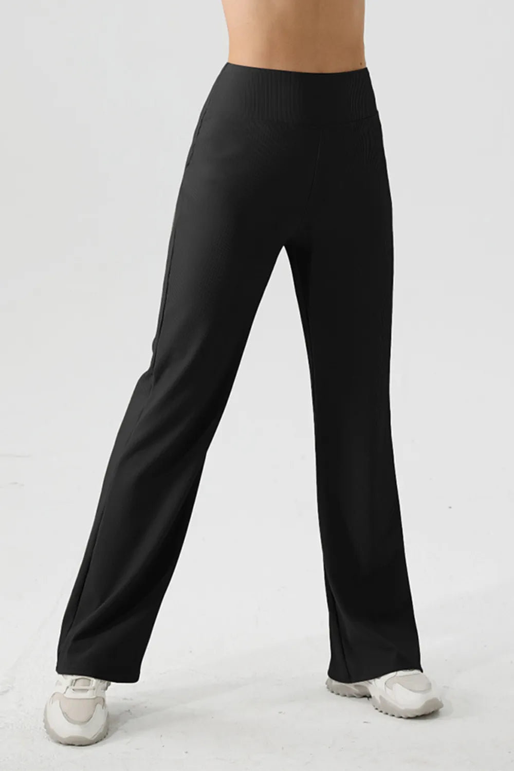 Person wearing black wide-leg pants on a white background