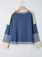 Blue and beige sweater on a hanger against a light gray background