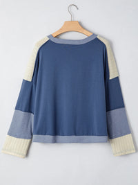 Blue and beige sweater on a hanger against a light gray background