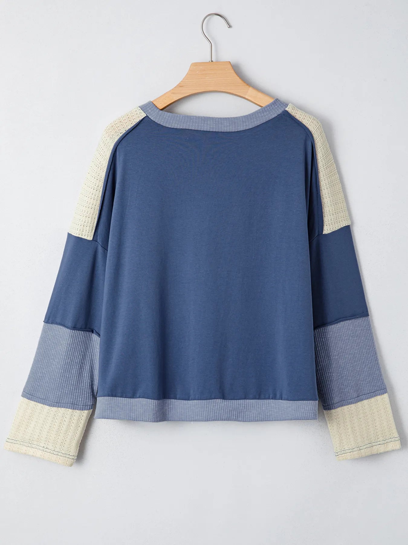Blue and beige sweater on a hanger against a light gray background