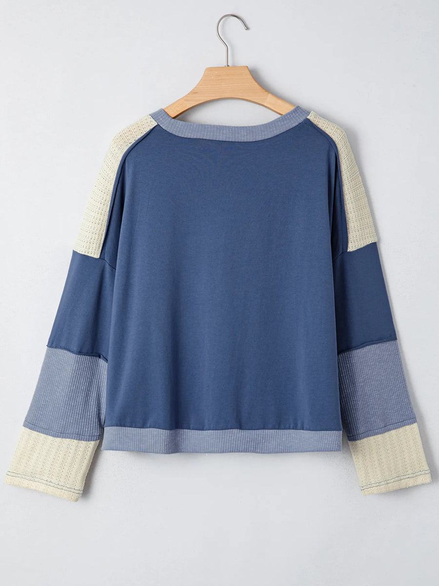 Blue and beige sweater on a hanger against a light gray background