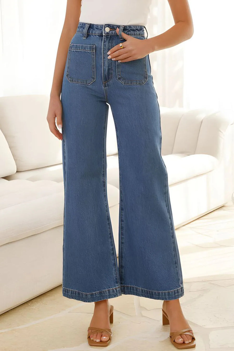 Person wearing blue jeans standing in a room with a white couch.