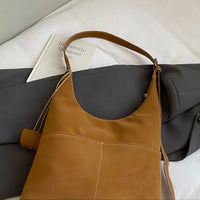 Brown leather bag on a gray surface with a book in the background