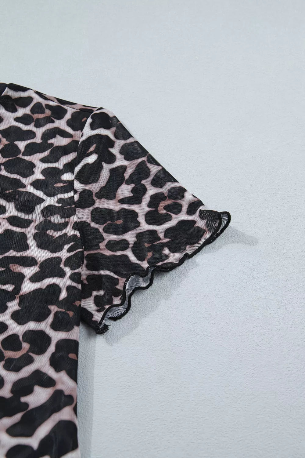 Leopard print fabric with ruffled edge on a light gray background