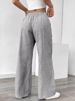 Person wearing gray and white striped wide-leg pants on a plain background