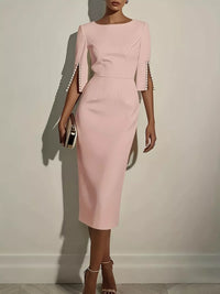 Pink dress with pearl embellishments on sleeves against a plain background