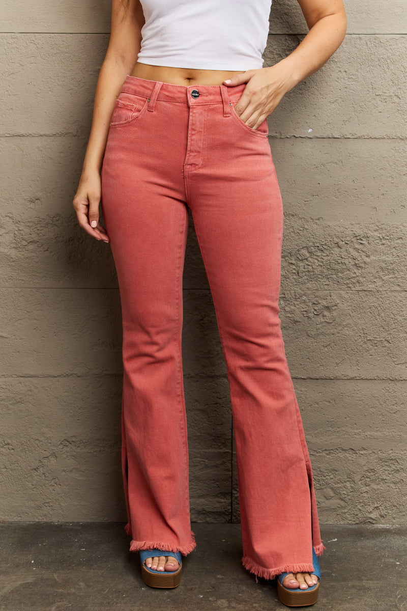 Person wearing pink flared jeans against a gray wall