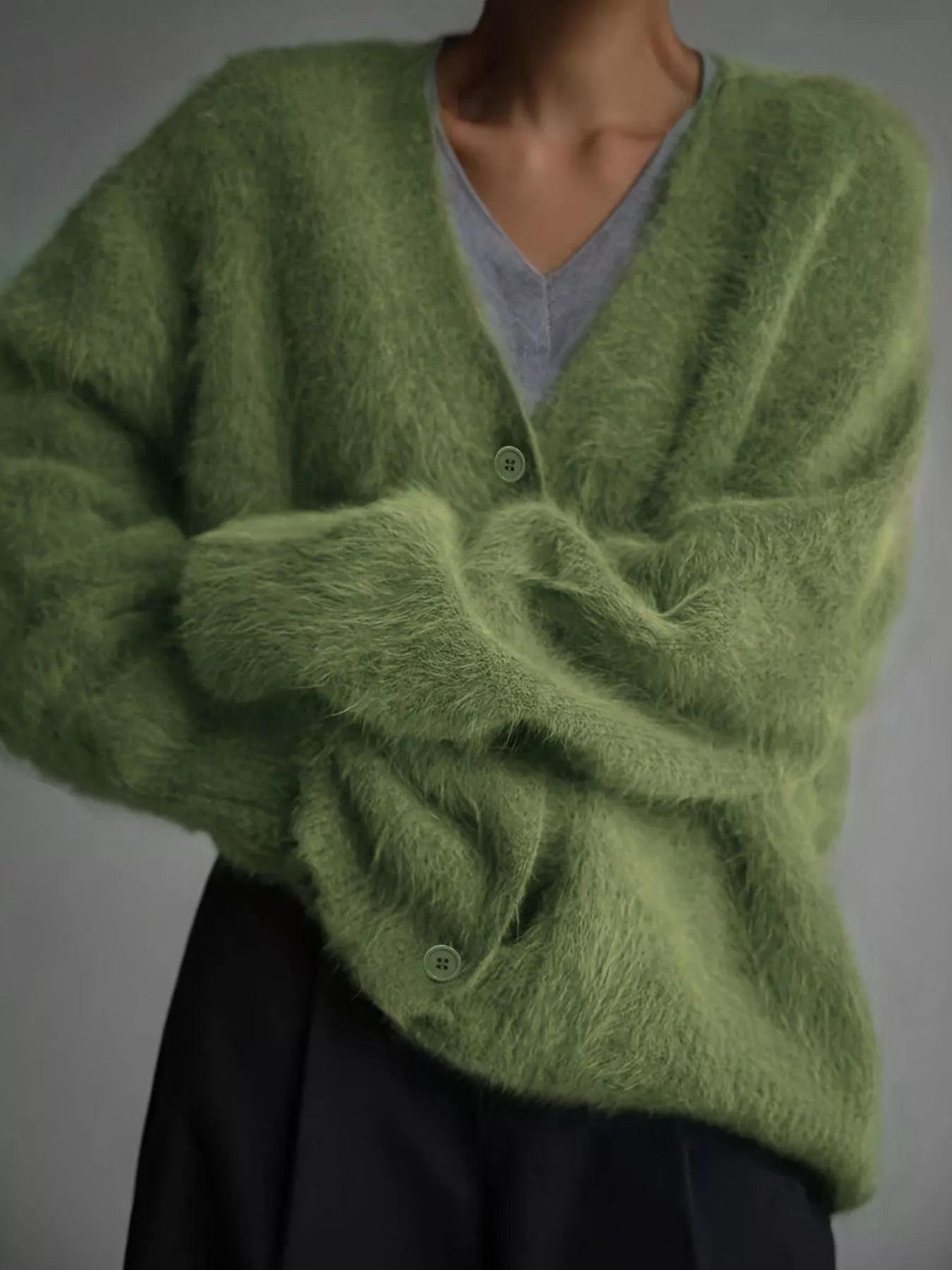 Green fuzzy cardigan worn by a mannequin against a gray background