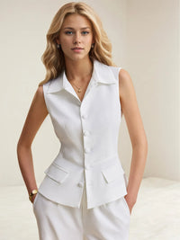 Woman wearing a white sleeveless blazer and pants against a plain background