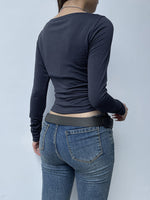 Person wearing a navy long-sleeve top and blue jeans against a light gray background