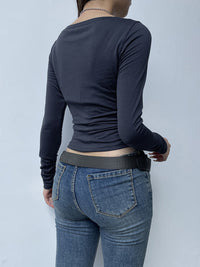 Person wearing a navy long-sleeve top and blue jeans against a light gray background