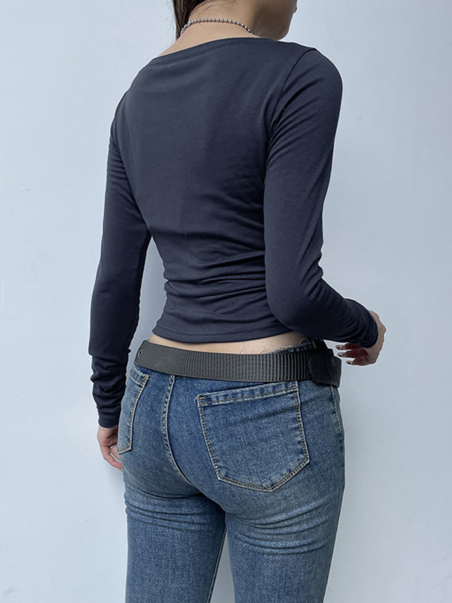 Person wearing a navy long-sleeve top and blue jeans against a light gray background