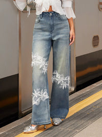 Person wearing blue jeans with white lace details on a train platform.