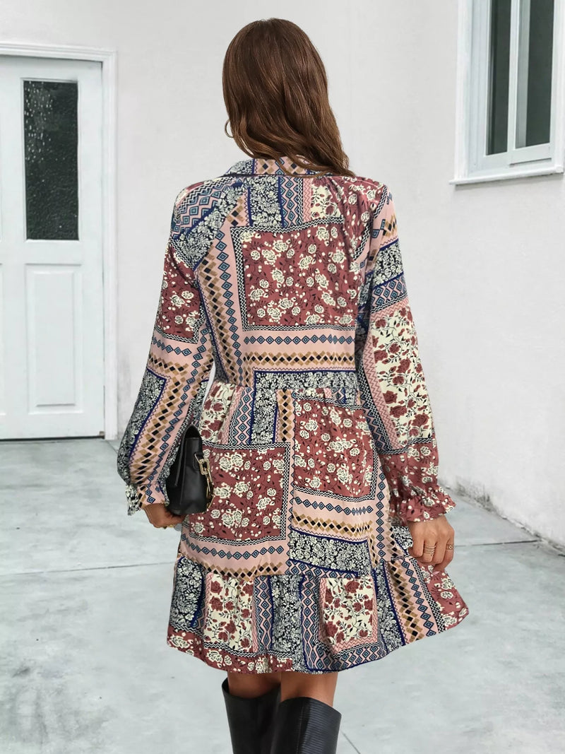 Woman wearing a patterned dress standing in a room with white walls and a door.