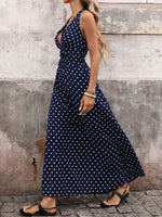 Woman wearing a navy blue dress with white polka dots against a textured wall.