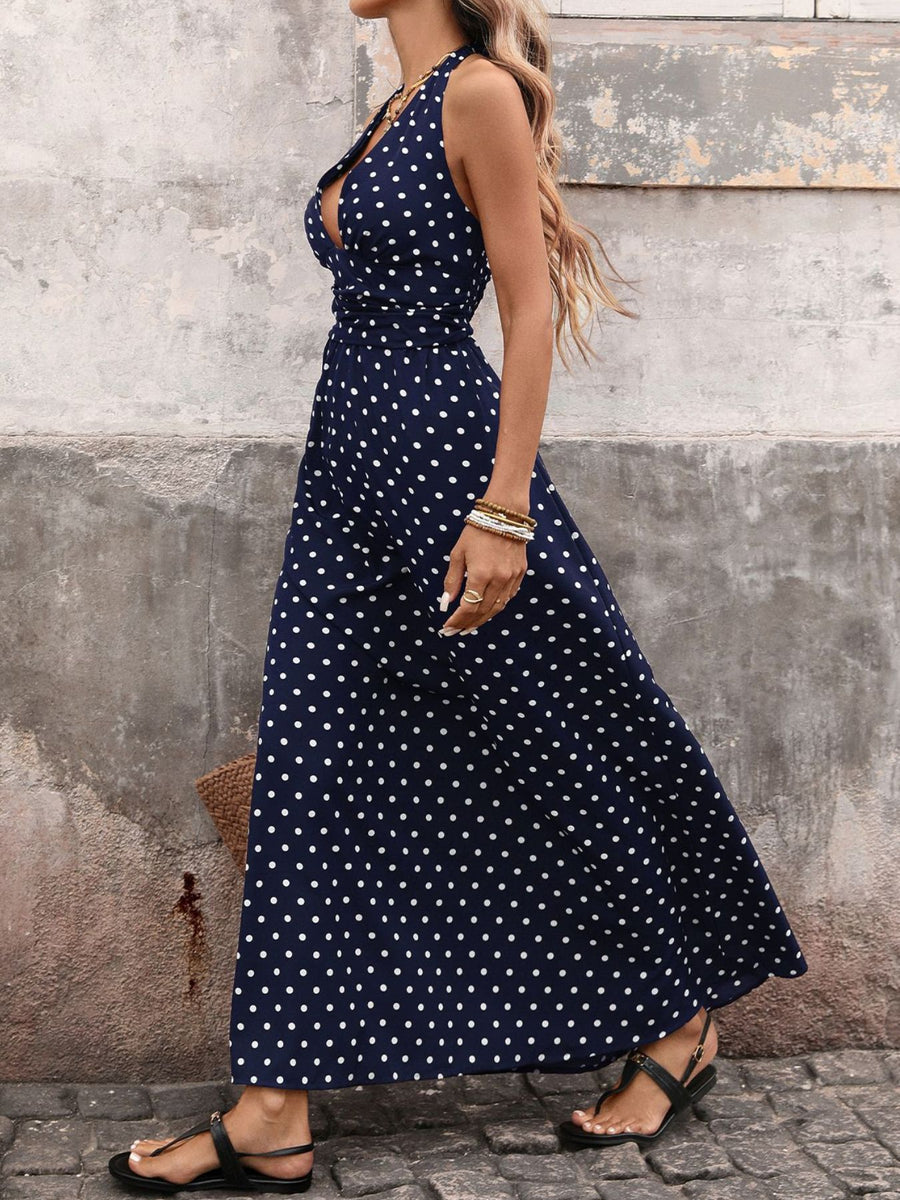 Woman wearing a navy blue dress with white polka dots against a textured wall.