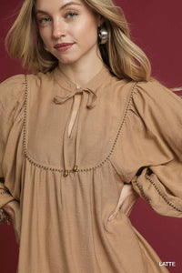 Woman wearing a brown dress with a maroon background