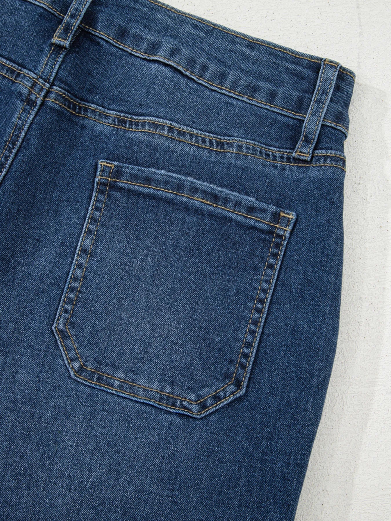 Close-up of a blue denim pocket on a light gray background