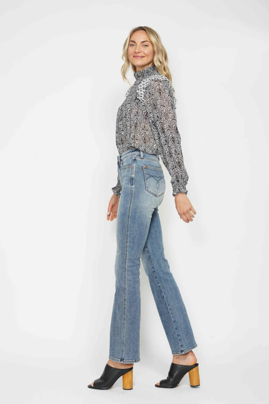 Woman wearing a patterned blouse and blue jeans on a white background