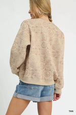Woman wearing a beige patterned sweater and denim shorts on a white background
