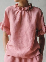 Pink linen top with ruffled sleeves on a plain background