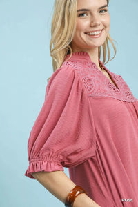 Woman wearing a pink blouse with lace details on a light blue background