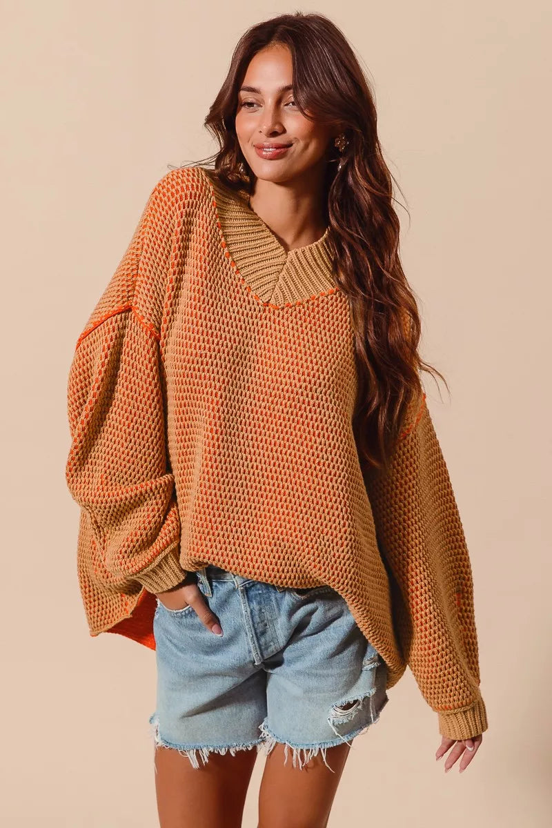 Woman wearing a brown knitted sweater and denim shorts against a beige background