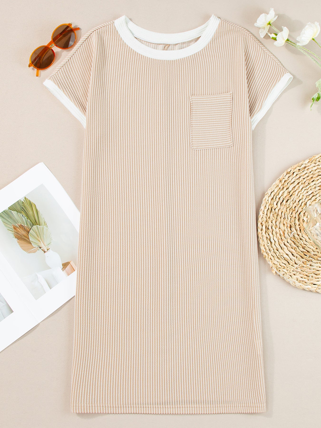 Beige ribbed dress on a light brown surface with sunglasses and flowers.