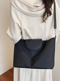 Person wearing a black shoulder bag with a neutral background