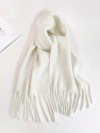 White scarf with tassels on a light gray background
