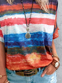 Person wearing a colorful striped shirt with a necklace and bracelet on a gray background