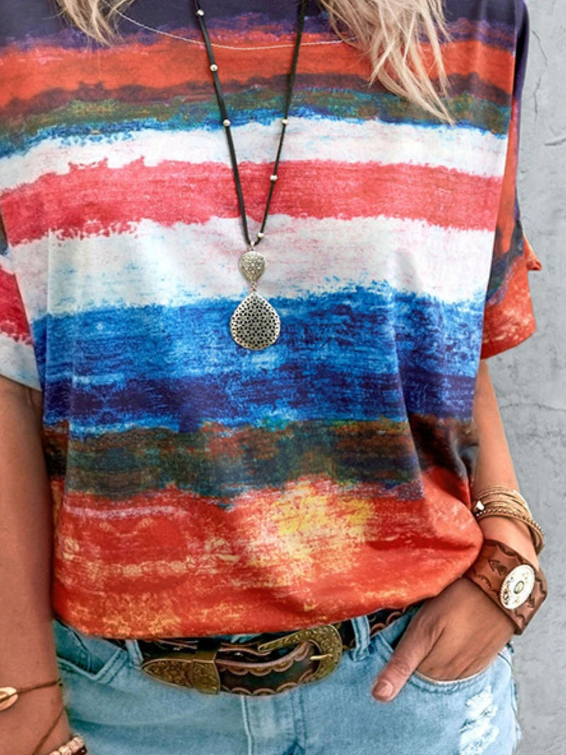 Person wearing a colorful striped shirt with a necklace and bracelet on a gray background