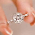 Diamond ring held between fingers with a blurred background
