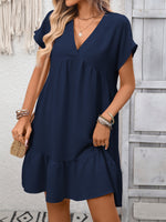 Woman wearing a navy blue dress with a neutral background