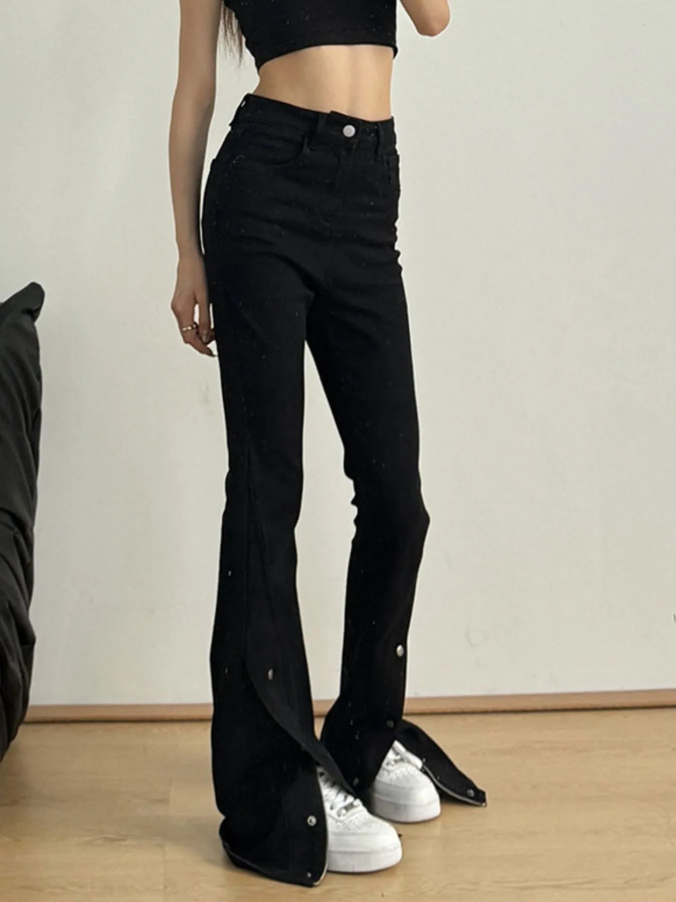 Person wearing black bell-bottom pants with a plain background